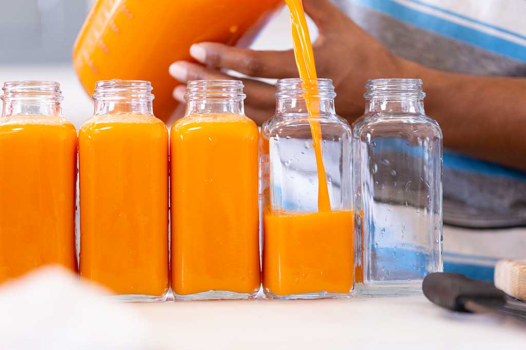 Image of pouring cold pressed juice in multiple glass jars