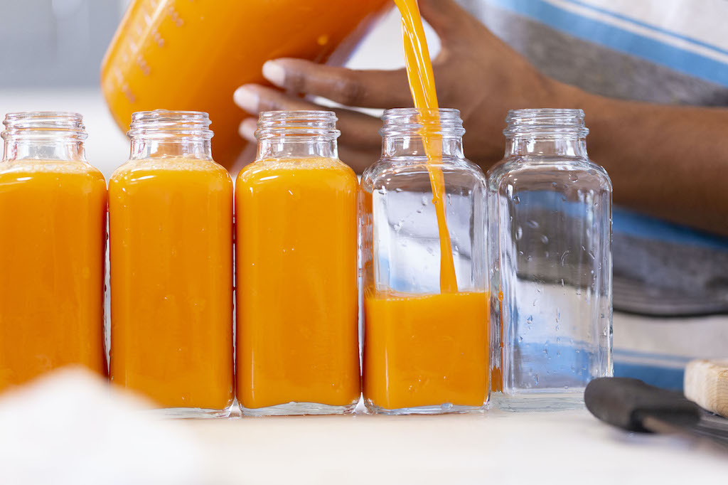 Pouring Power Roots Turmeric Juice Into Bottles