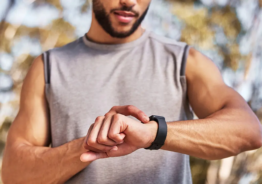 A male athlete checking his smart watch.